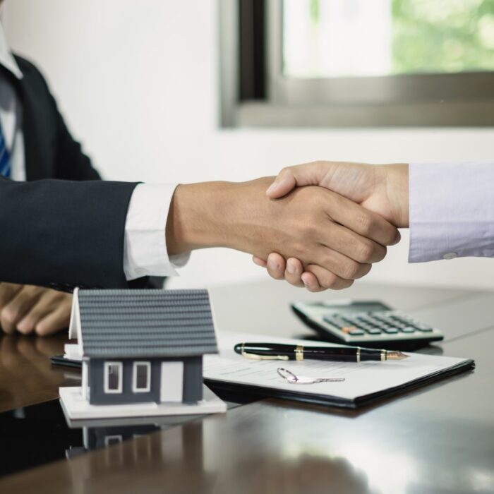 Businessmen and brokers real estate agents shake hands after completing negotiations to buy houses insurance and sign contracts. Home insurance concept.